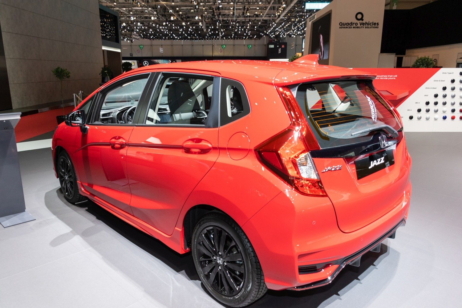 Rear side view of red hatchback with angular taillights and black wheels