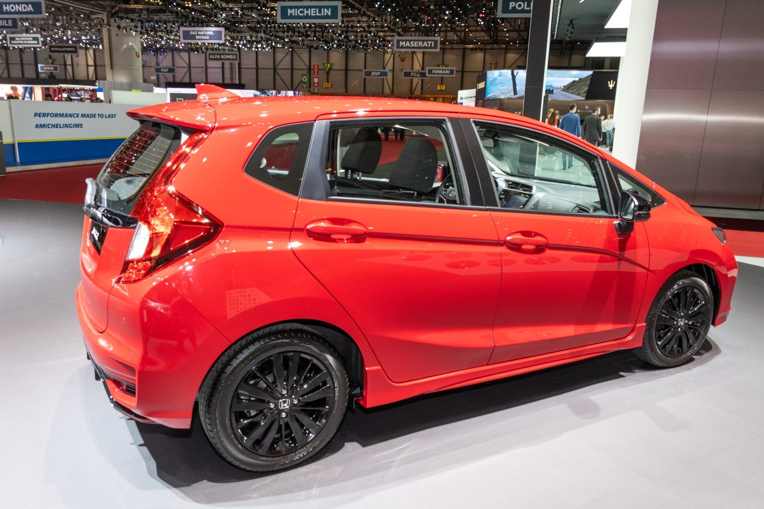 Red five-door hatchback with black alloy wheels and tinted windows