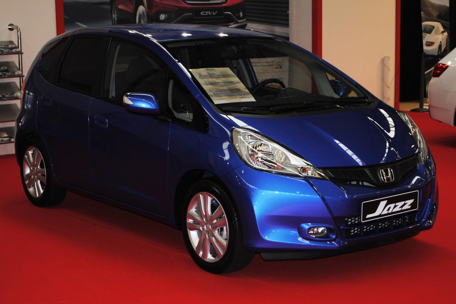 Blue compact hatchback front view with headlights and grille