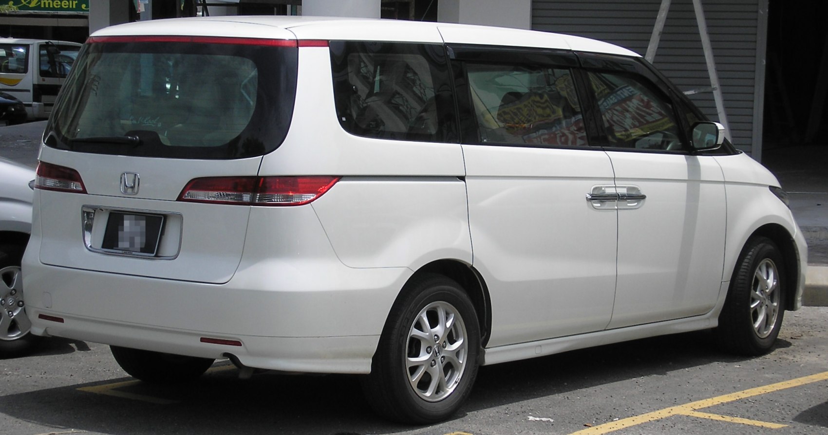 Rear and side view of a white minivan with sliding door and distinctive tail lights