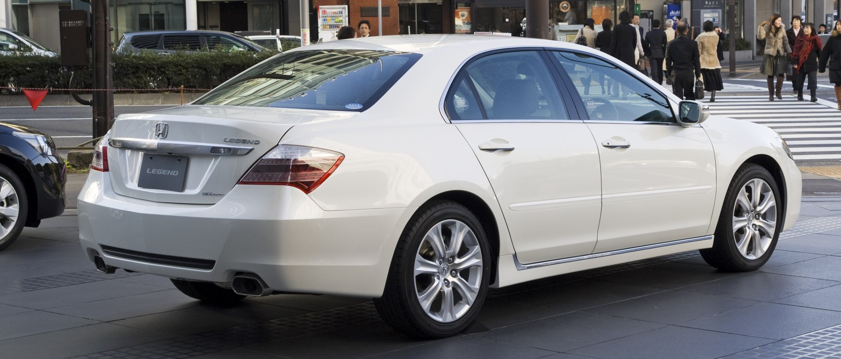 Rear side view of white sedan with alloy wheels in urban setting