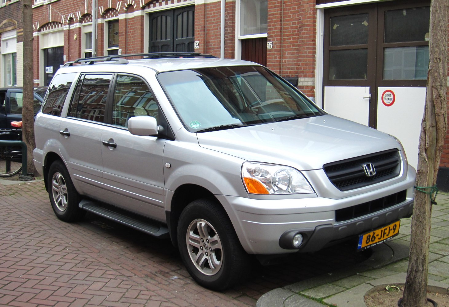 Silver SUV with front headlights and roof rails in city parking