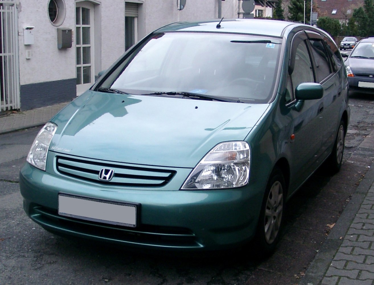 Compact car front with headlights and grille in urban street.