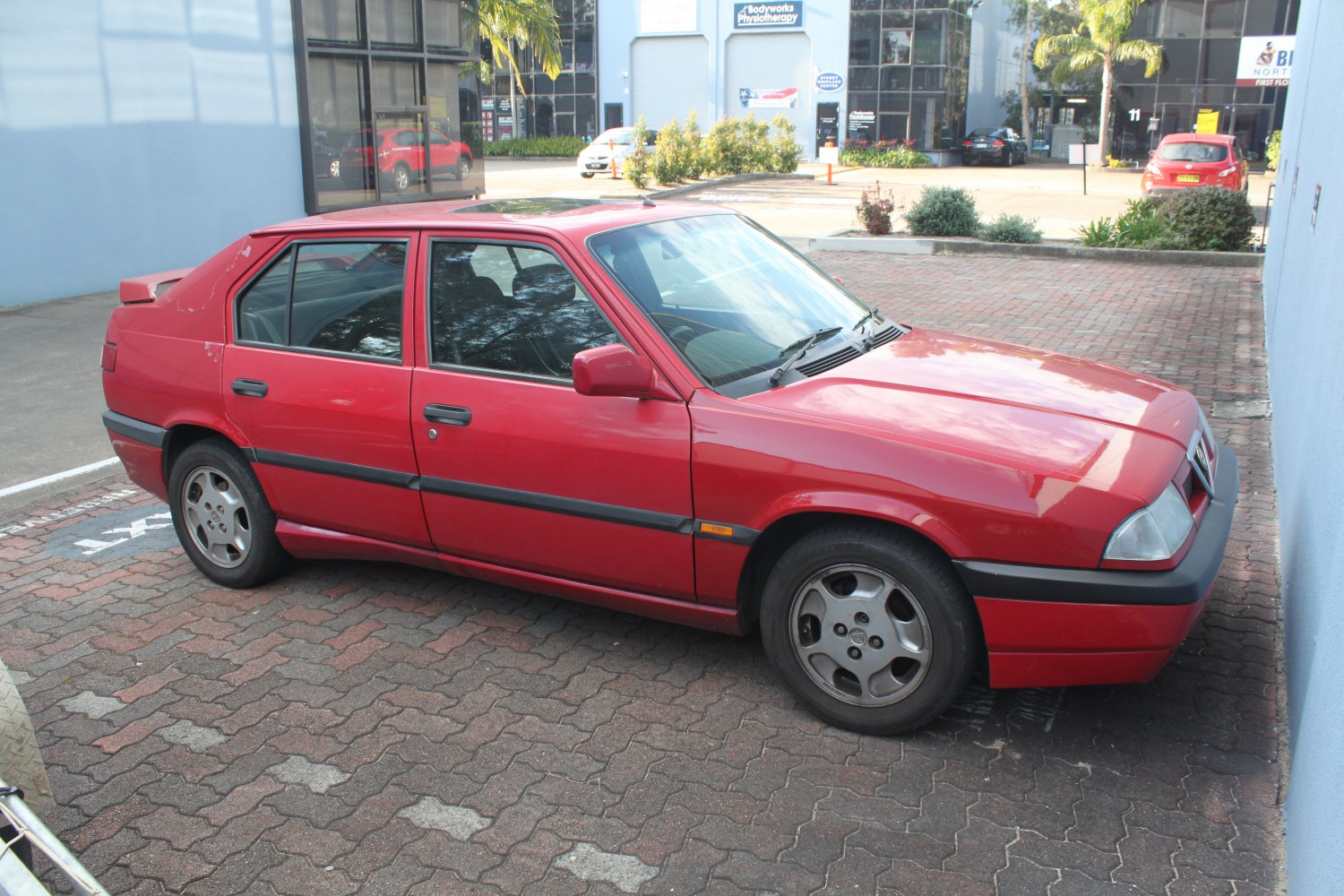 Red sedan with boxy design and alloy wheels side profile