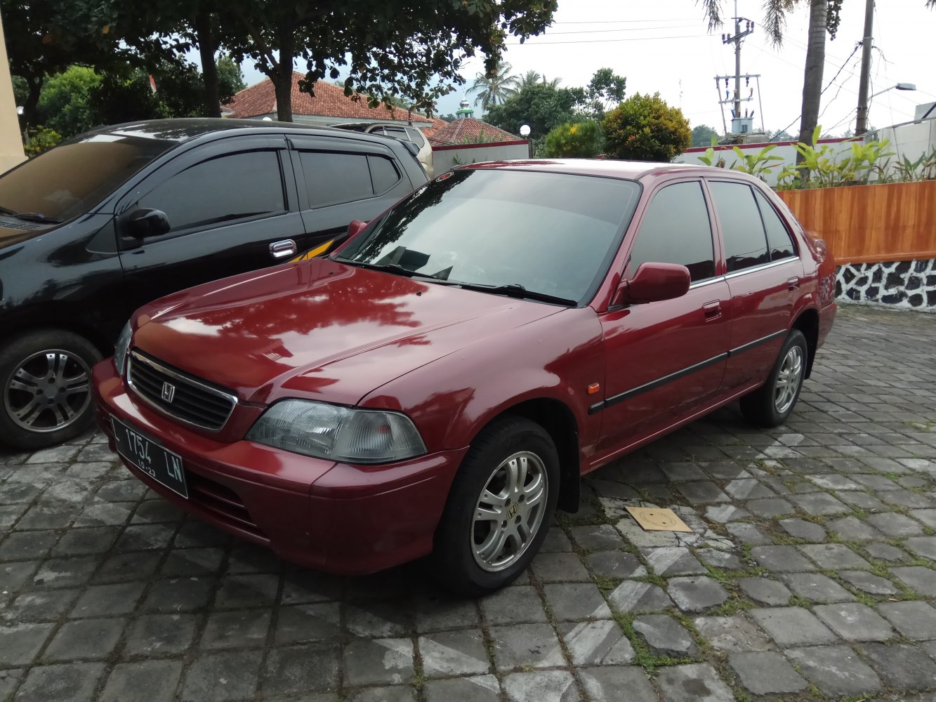 Red sedan front-side with headlamps and alloy wheels