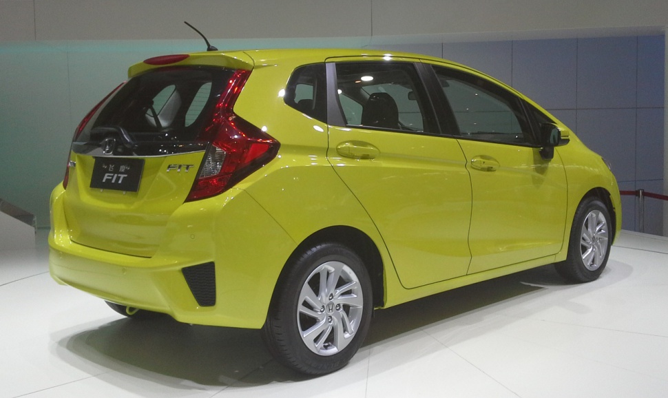 Bright yellow compact hatchback rear-side view with alloy wheels and distinct taillights.