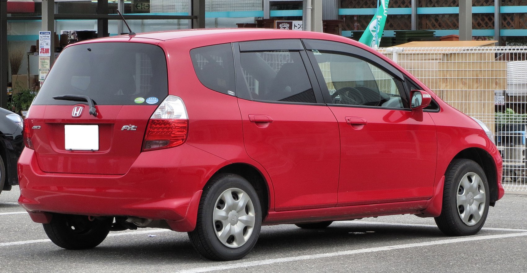 Rear side view of red compact hatchback with tinted windows and taillights