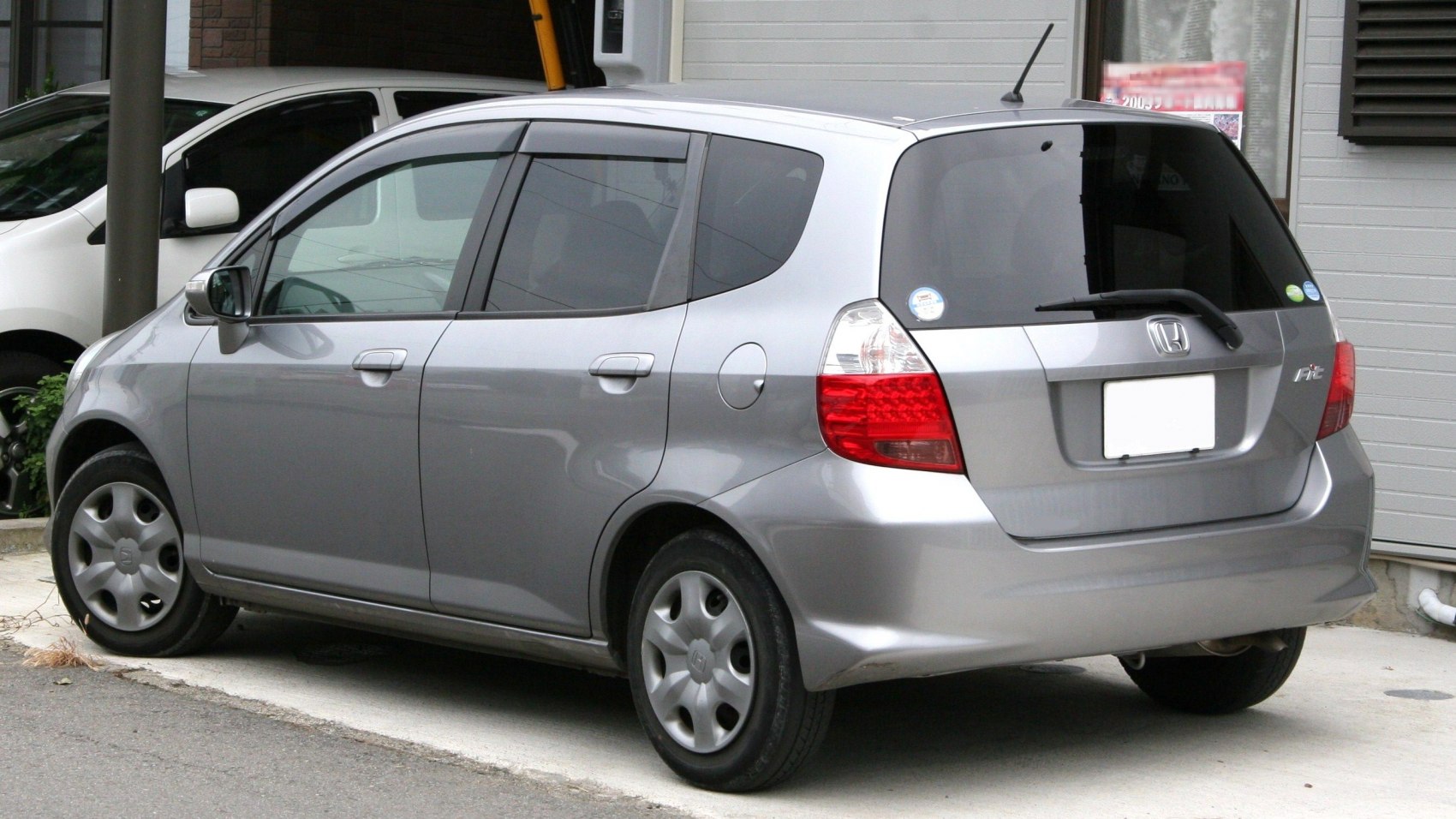Rear side of a compact hatchback featuring triangular tail lights and simple wheel covers