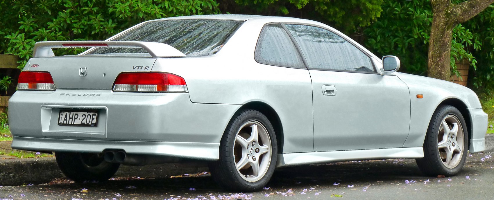Rear-side view of silver sports coupe with spoiler and alloy wheels
