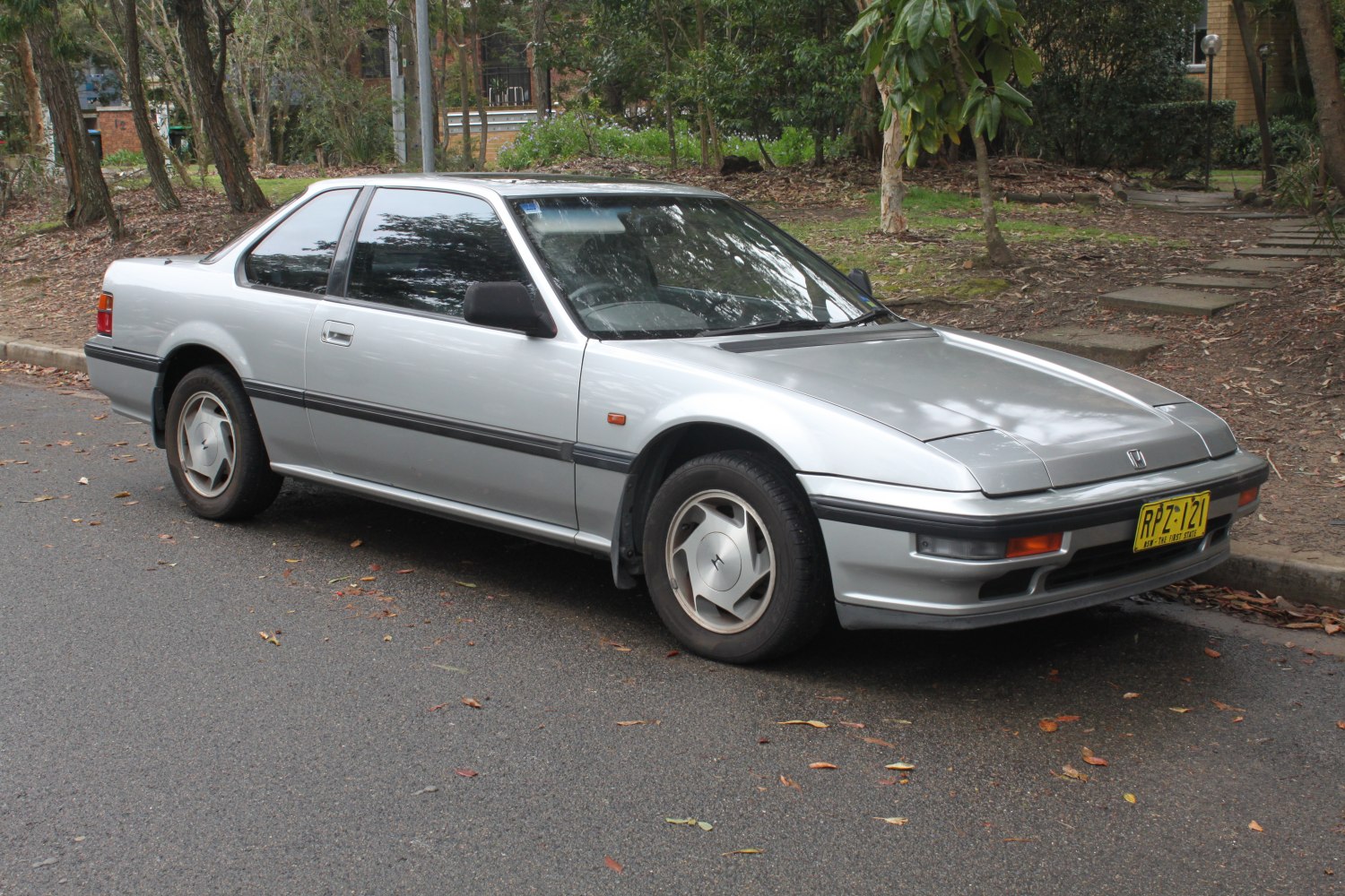 Silver coupe with pop-up headlights parked on street