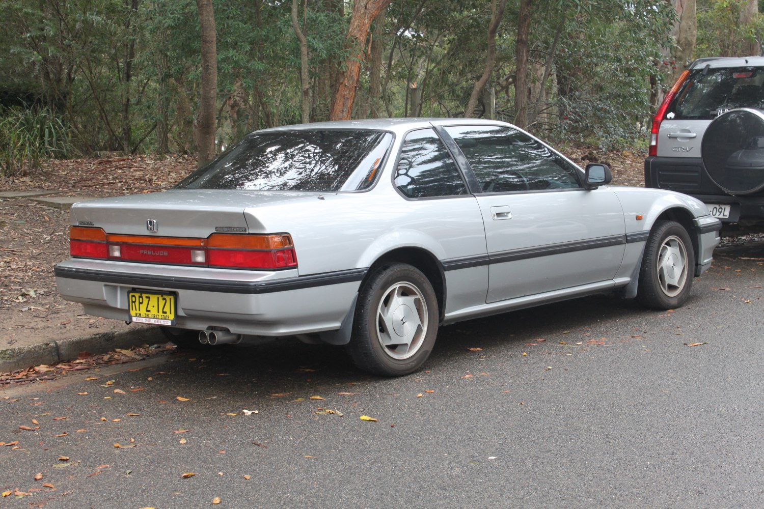 Silver coupe rear side with dual exhaust and tinted windows