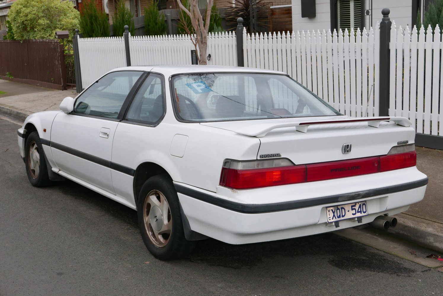Rear side view of a 1980s coupe with spoiler and distinct taillights