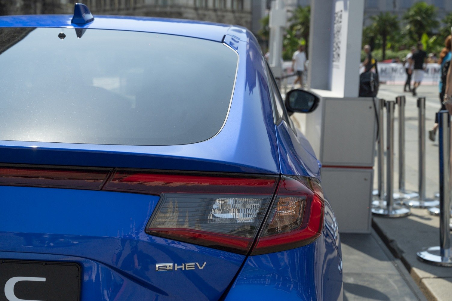 Rear end and tail light with hybrid badge