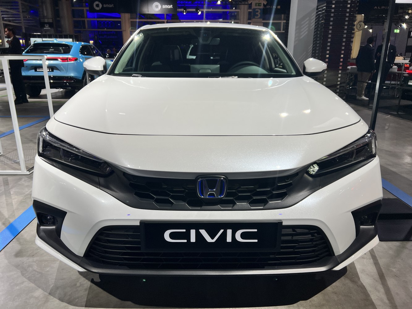 Front grille and modern LED headlights of a white sedan.
