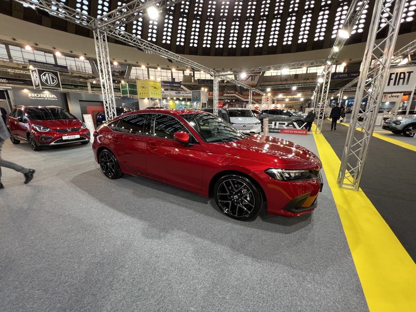 Glossy red sedan with black alloy wheels at auto show