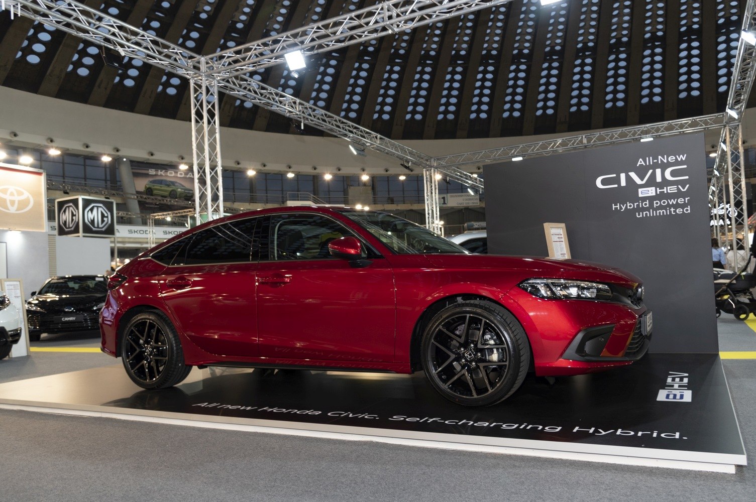 Red compact hatchback with black alloy wheels and sleek aerodynamic design