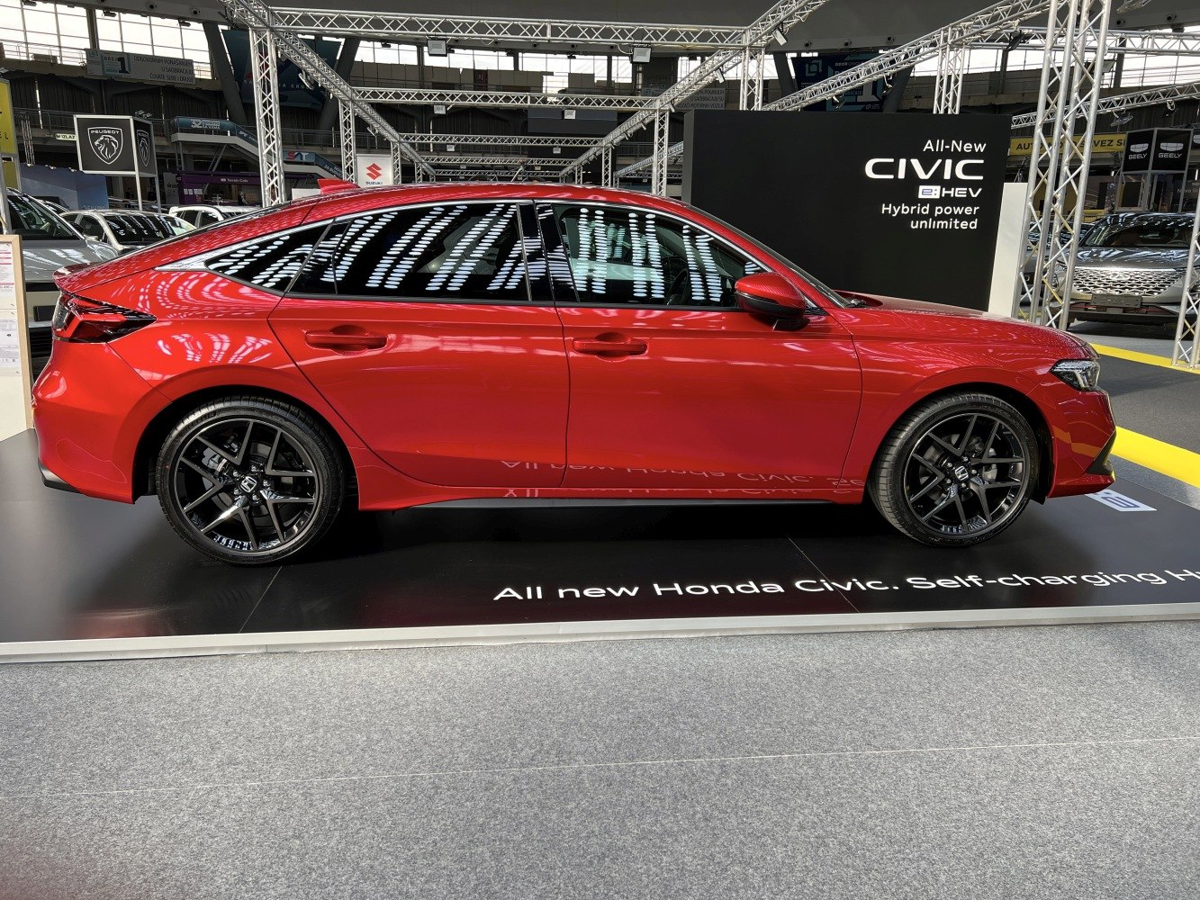 Red hatchback side profile with black alloy wheels