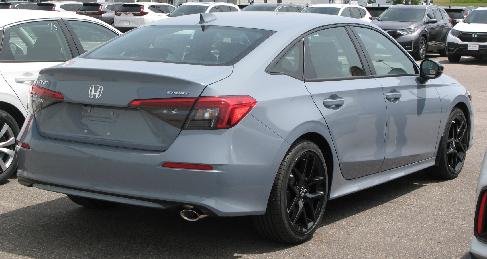 Rear and side view of a sedan with sport badge and black alloy wheels.