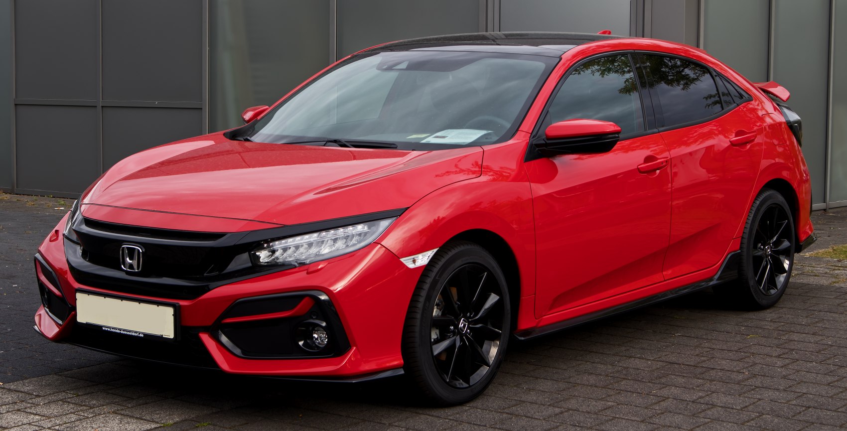 Sporty red hatchback with black alloy wheels and aggressive front design