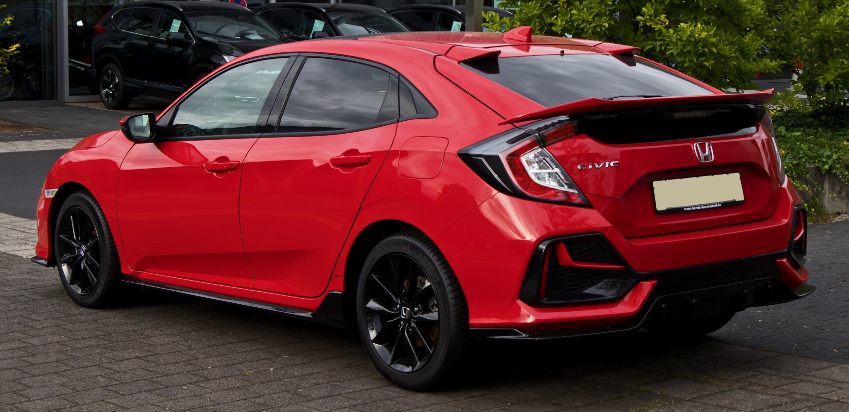 Red hatchback rear and side view with black alloy wheels and sporty spoiler