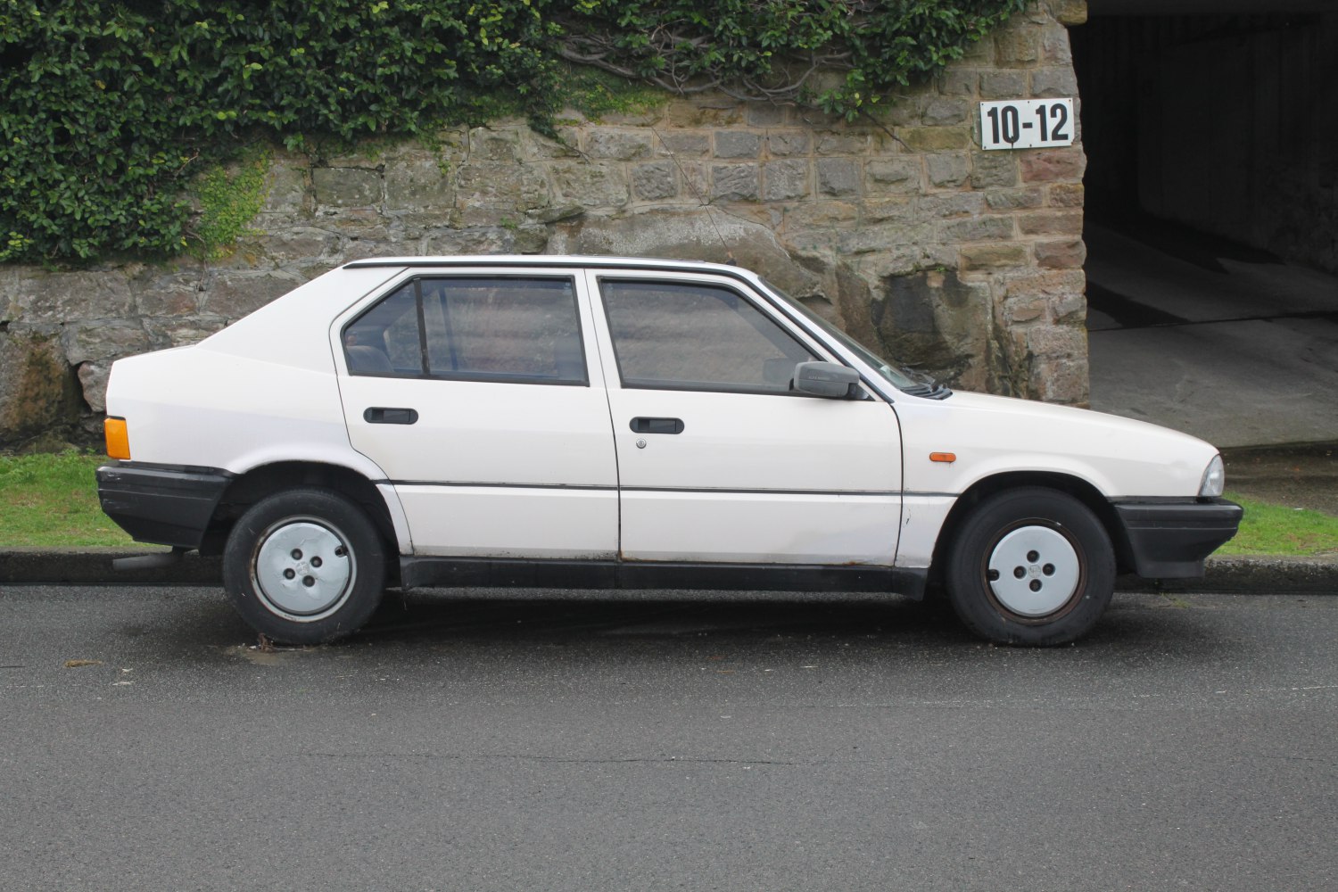 White sedan side view with polygonal rear and circular hubcaps