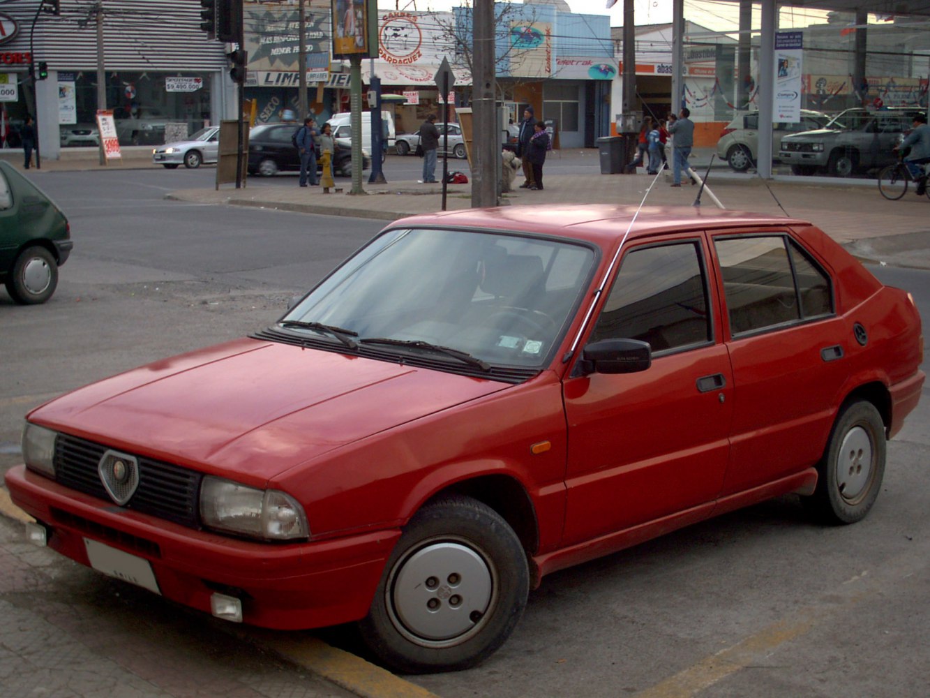 Red four-door hatchback with rectangular headlights and unique wheel covers