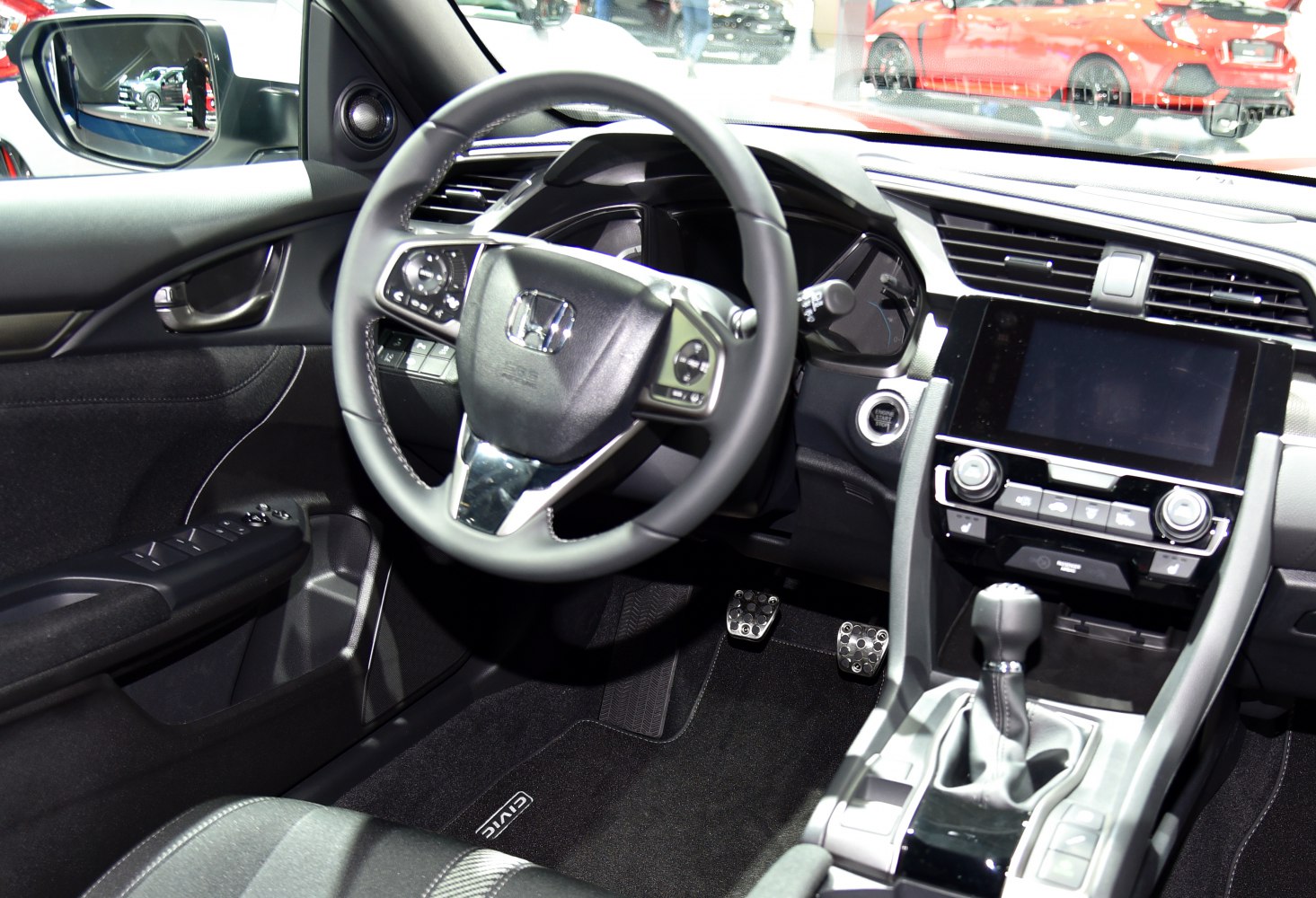 Steering wheel, manual gear shifter, and dashboard with controls and pedals