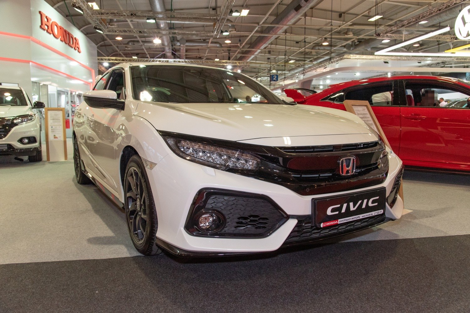 Sporty front and side of a white hatchback with LED headlights and aggressive grille