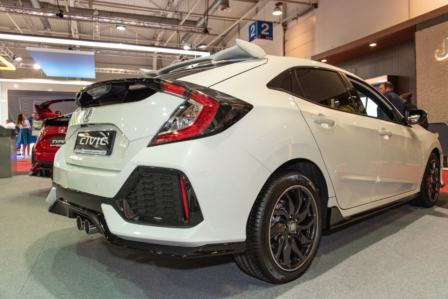 Rear view of a hatchback with spoiler, dual exhaust, and black alloy wheels