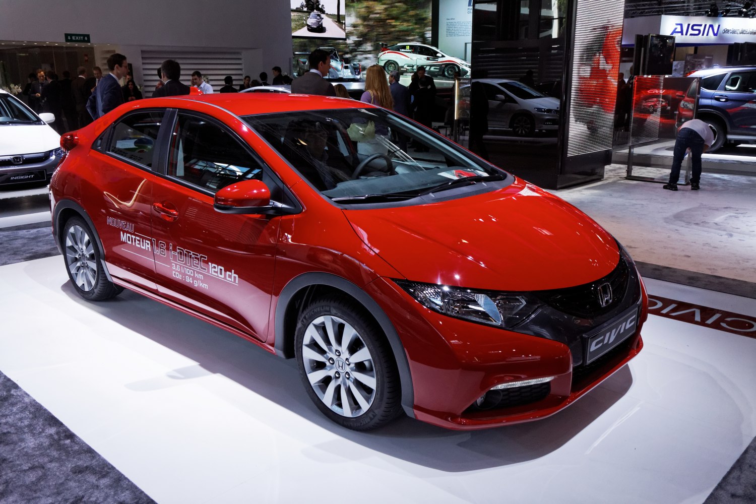 Red compact hatchback with sharp headlights and alloy wheels.