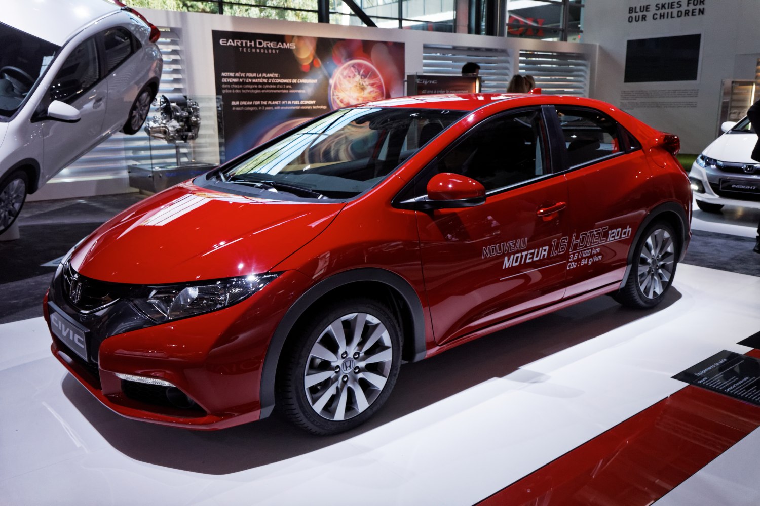 Red hatchback with sporty front fascia and engine specs decal on side