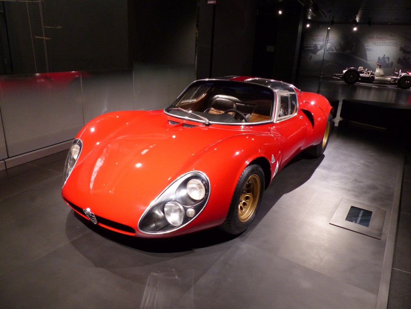 Red 1967 sports car with round dual headlights and smooth curved body.