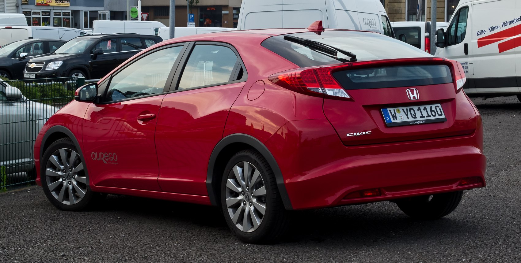 Rear side view of a red hatchback with distinctive tail lights and alloy wheels