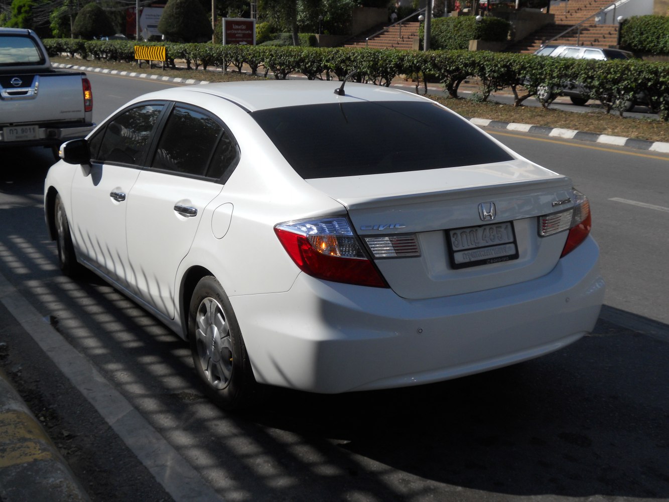 Rear-side view of white compact sedan with tinted windows and clear tail lights
