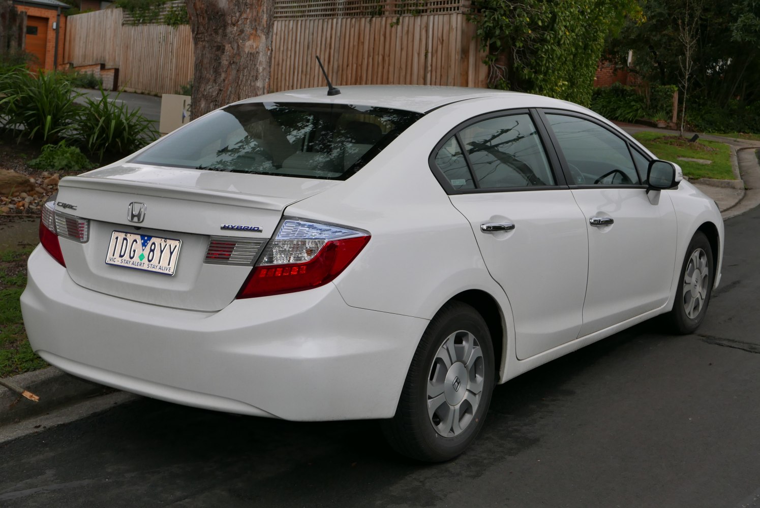 Rear-side view of white hybrid sedan with distinct tail lights and hybrid badge