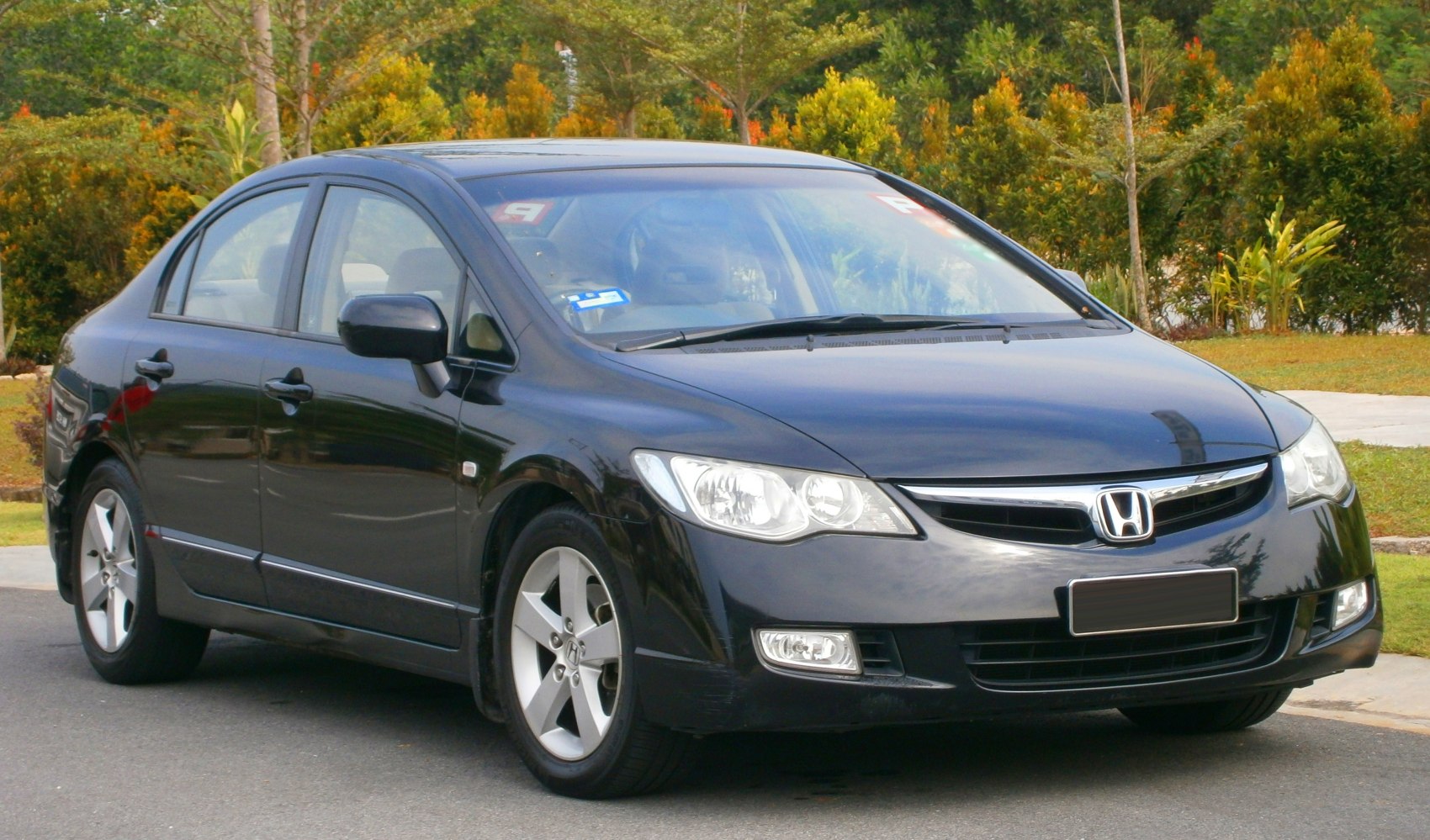 Front side view of black sedan with headlights and alloy wheels