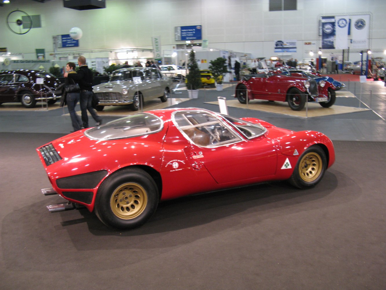 Side view of sleek red sports coupé with gold wheels and prominent rear vents