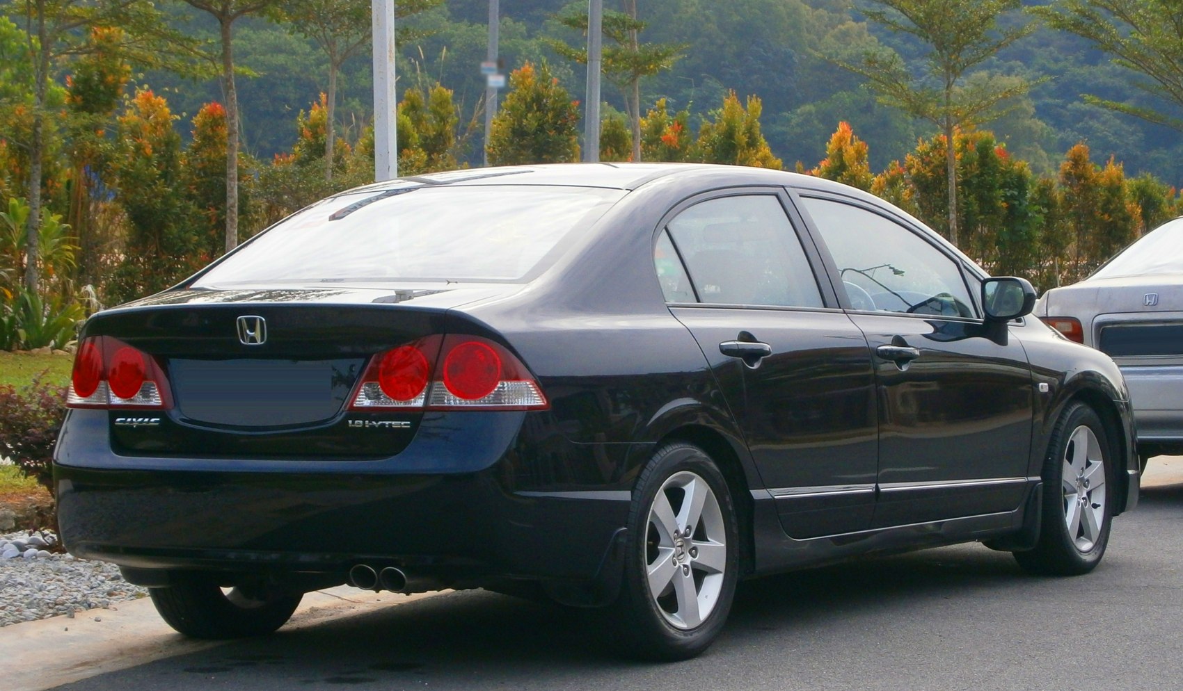 Rear three-quarter view of a black sedan with distinct taillights and alloy wheels