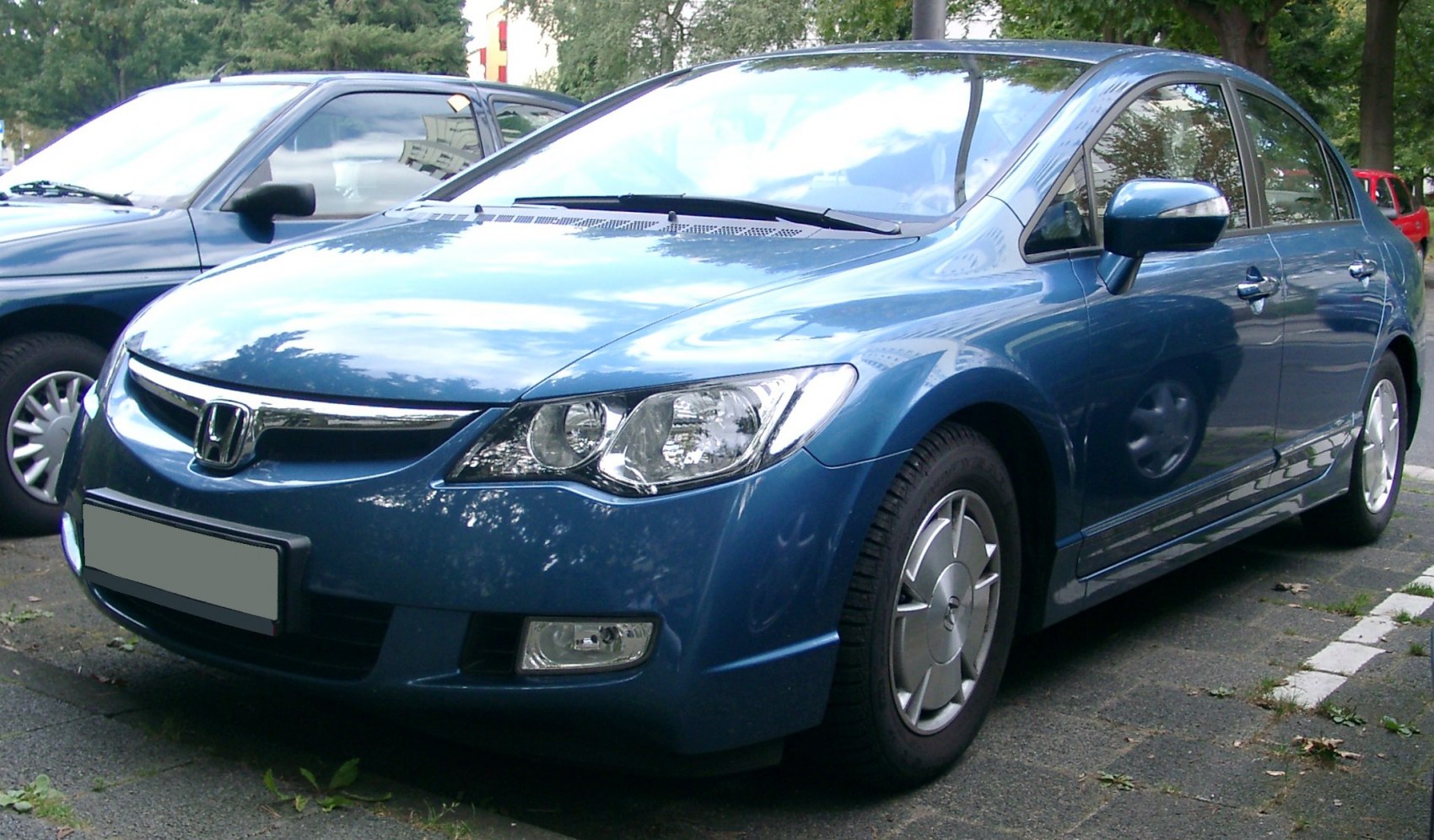 Front and side view of blue sedan with distinctive headlights and alloy wheels