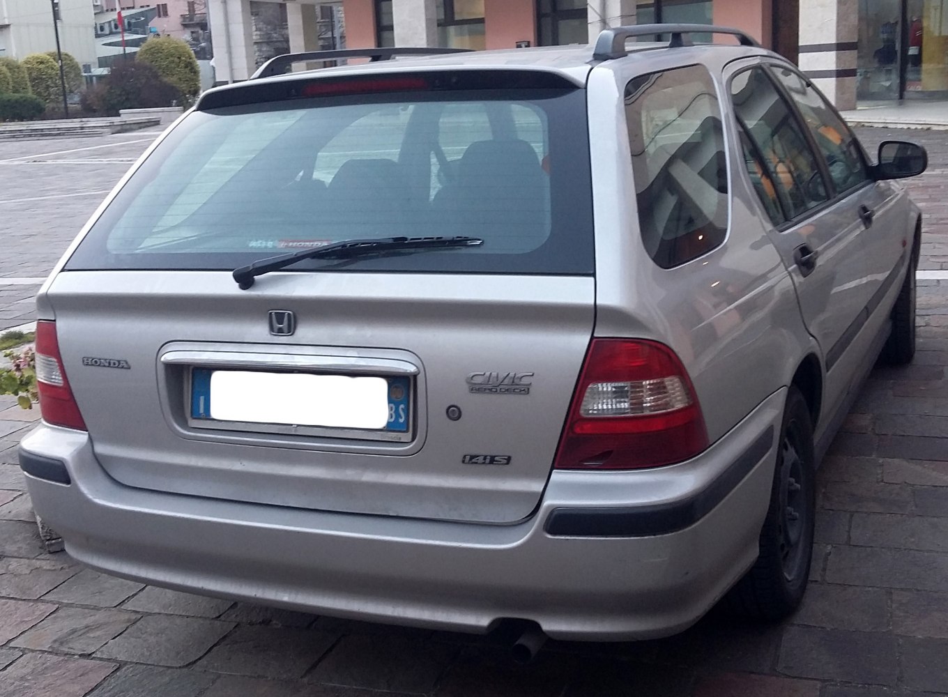 Rear view of a late 1990s silver estate car with distinct tail lights and roof spoiler
