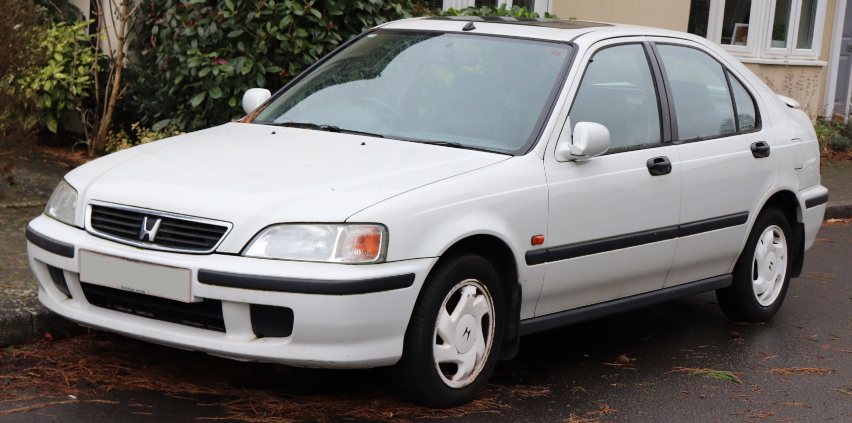 White compact sedan front left view with headlight and grille