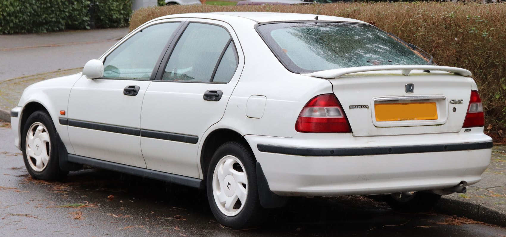 Rear side view of white sedan with spoiler