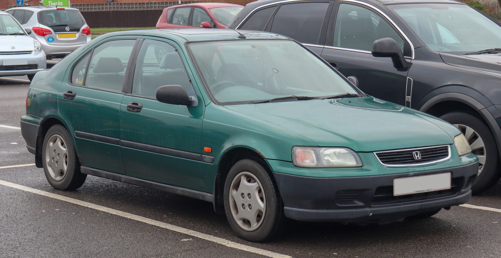 Side view of a green compact sedan with fastback design and four doors.