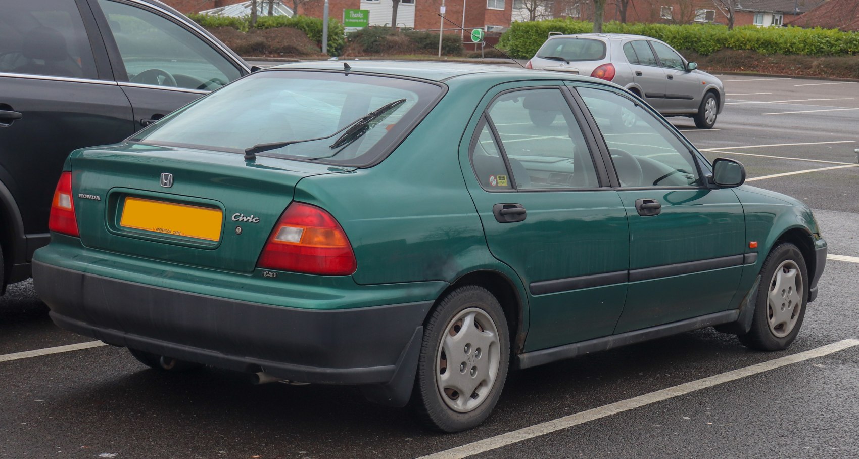 Rear side view of a green fastback sedan with visible rear wiper and four doors