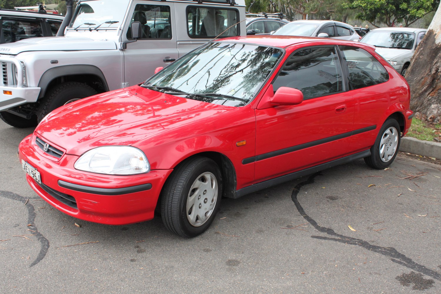 Red compact hatchback with rounded headlights and black trim side molding.