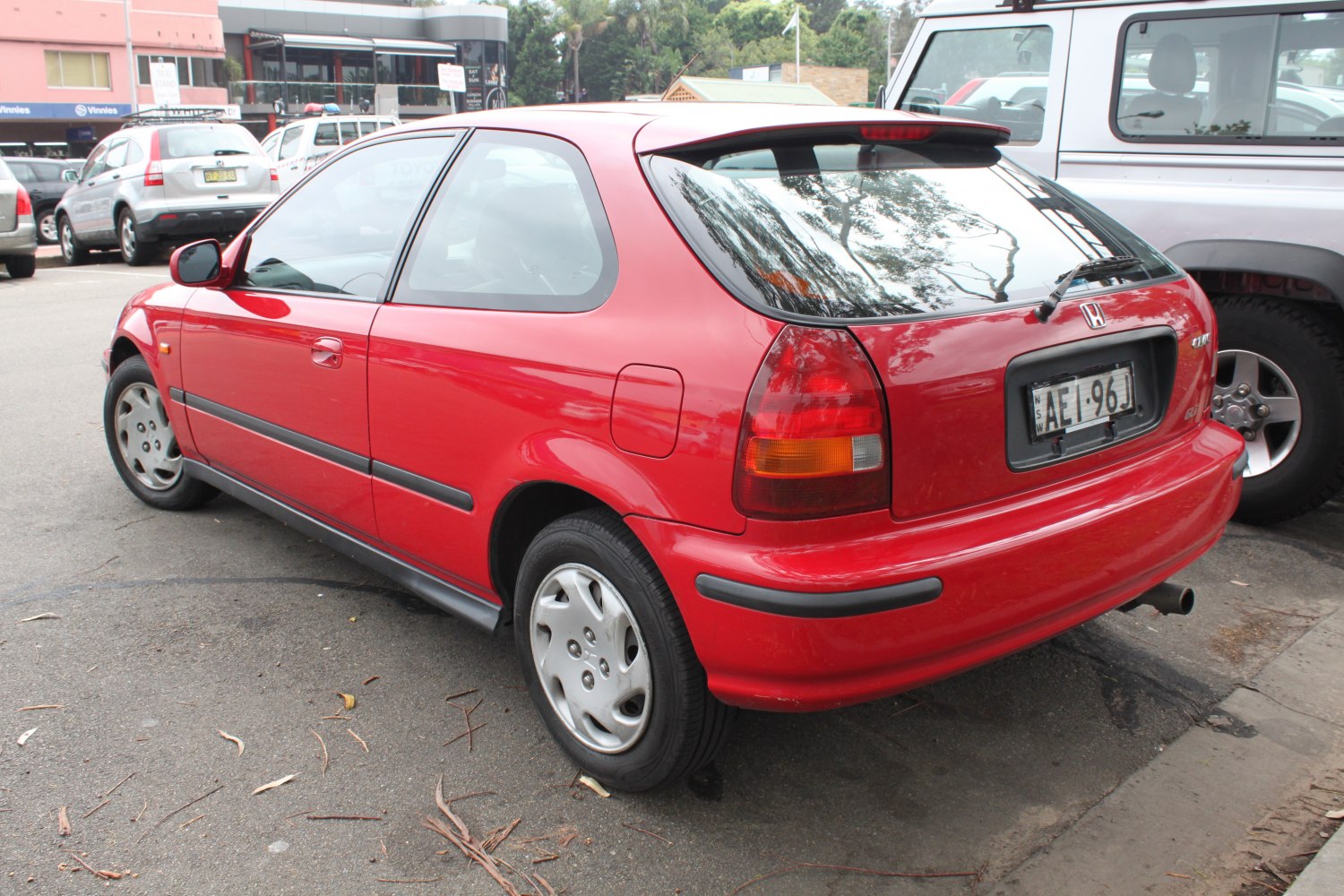 Rear side view of red hatchback with distinct taillights and compact design