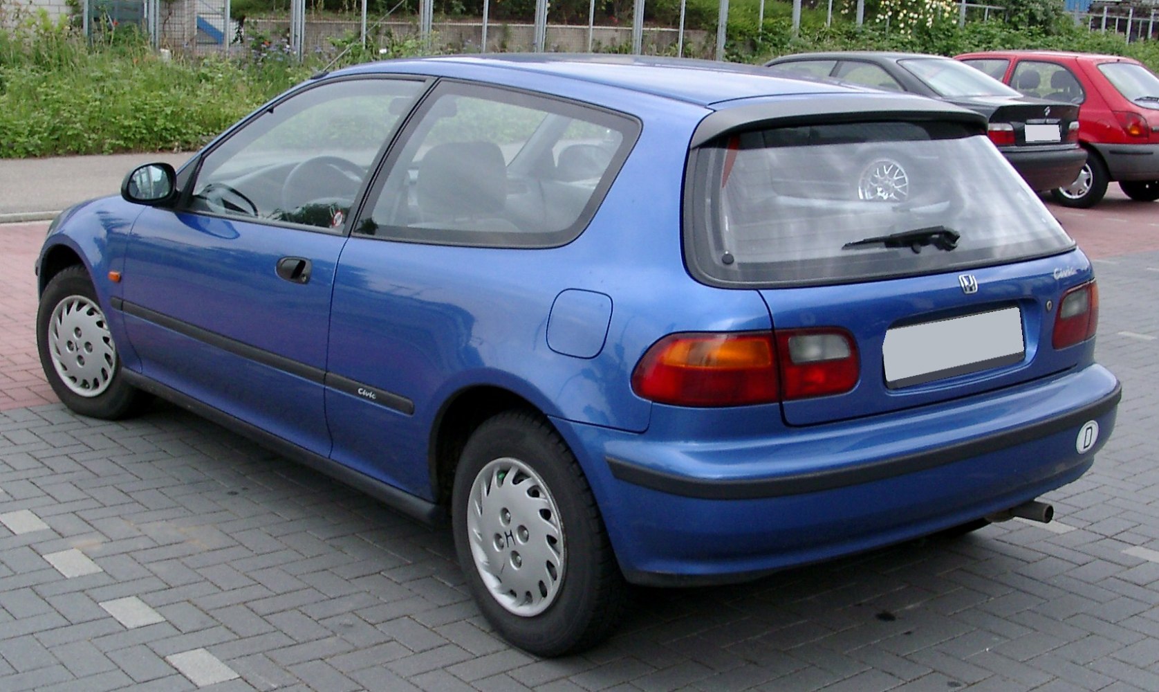 Rear side view of a blue two-door hatchback with rear wiper