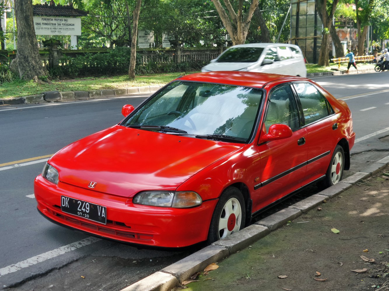 Red mid-90s sedan with rounded headlights and white wheels