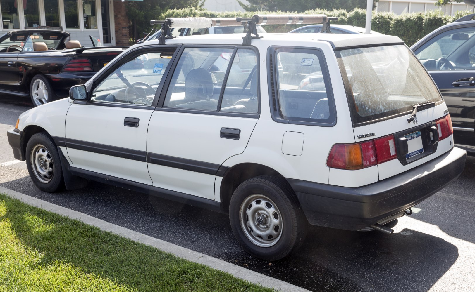 White station wagon with roof rack showing side and rear design