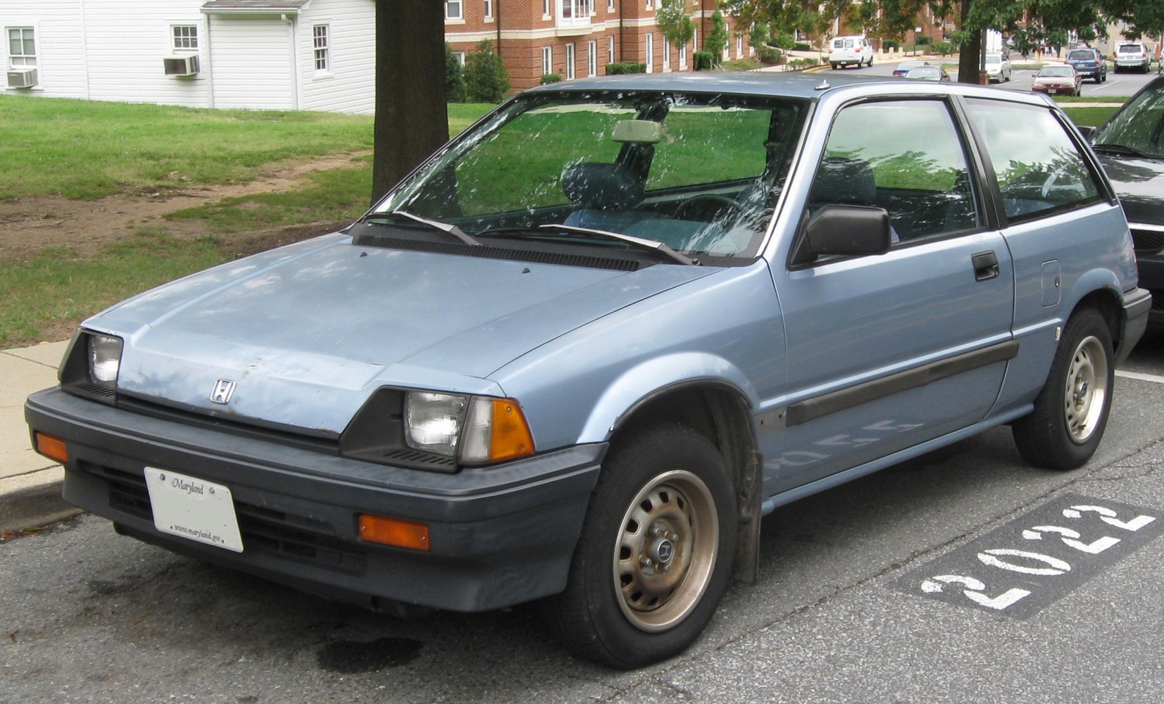 Classic blue hatchback with pop-up headlights and front side view.